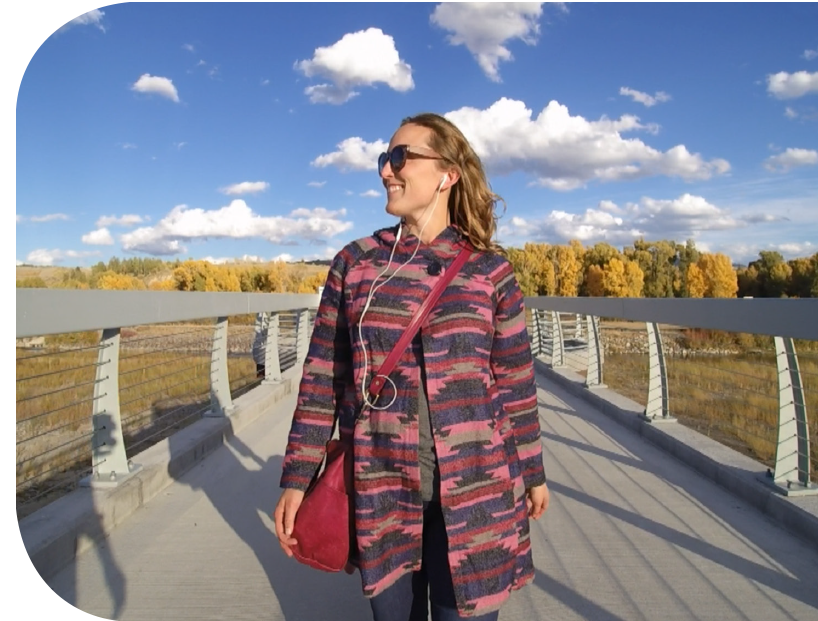 Woman walking on bridge using mobile audio tour